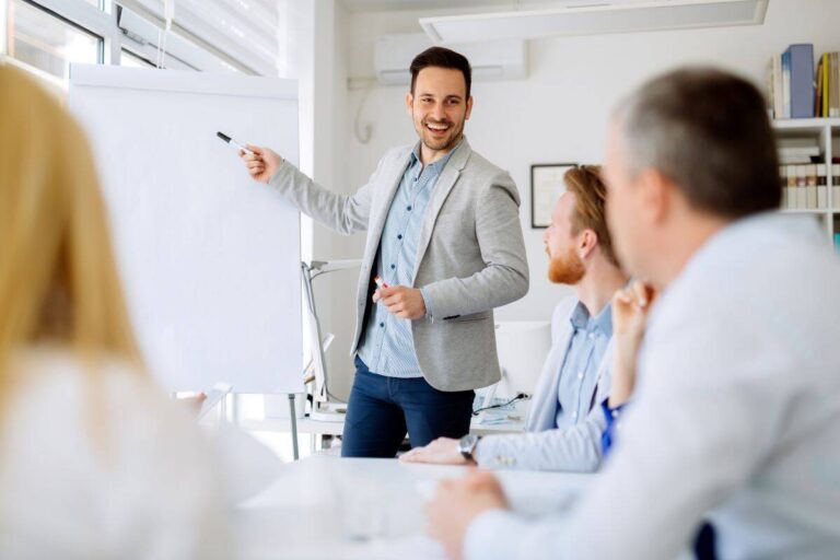 Un formateur expliquant un métier à un groupe de personnes, représentant le rôle de formation et de transmission de compétences.