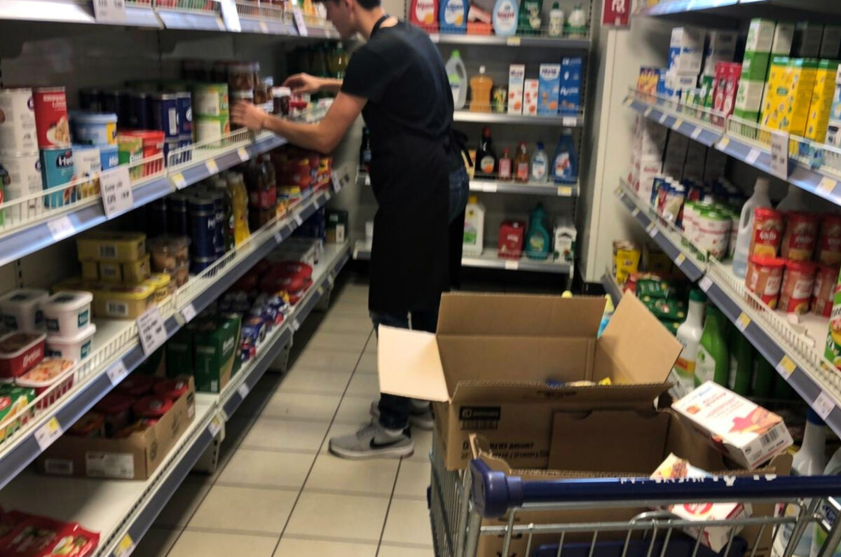 Jeune employé en tablier réassortissant des rayons