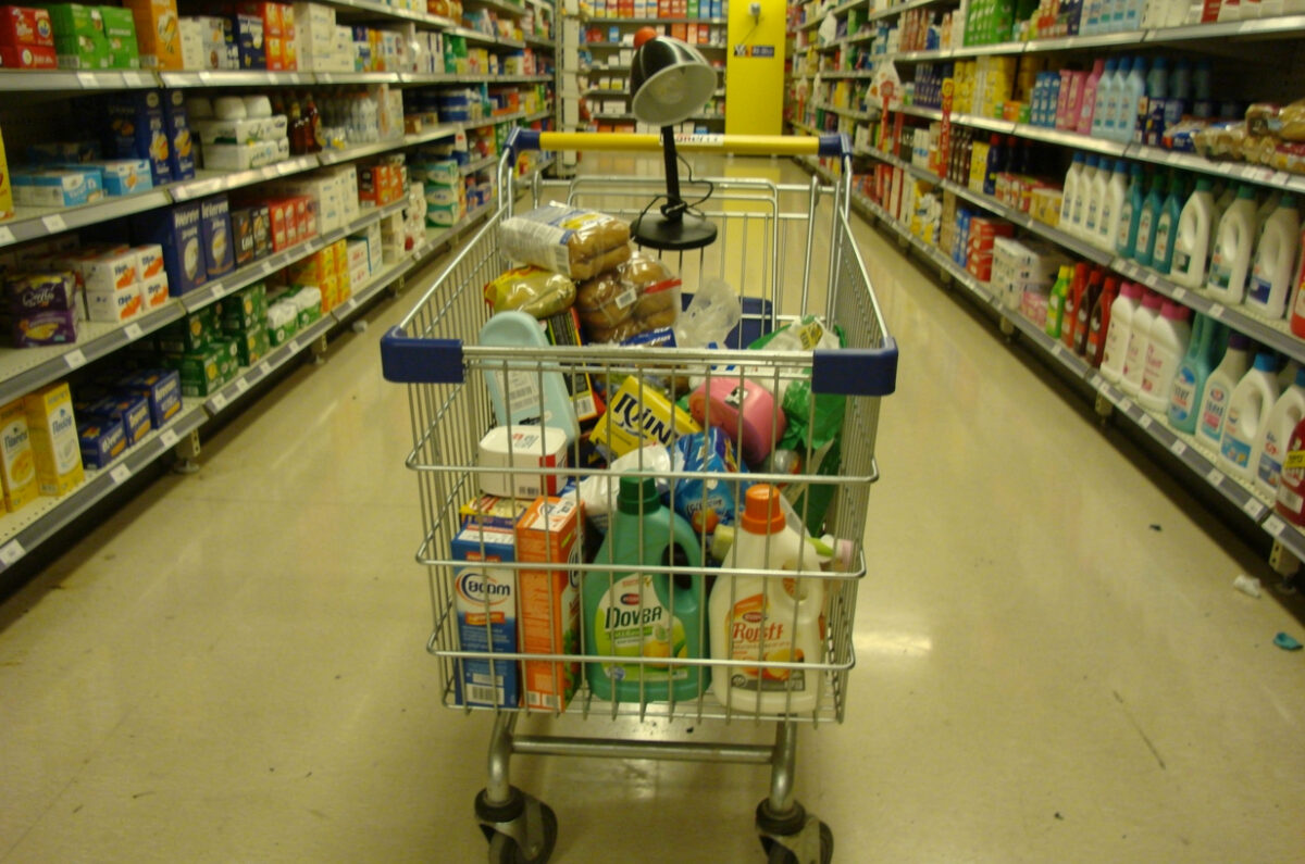 Chariot de supermarché rempli de produits de base et d'une lampe de bureau